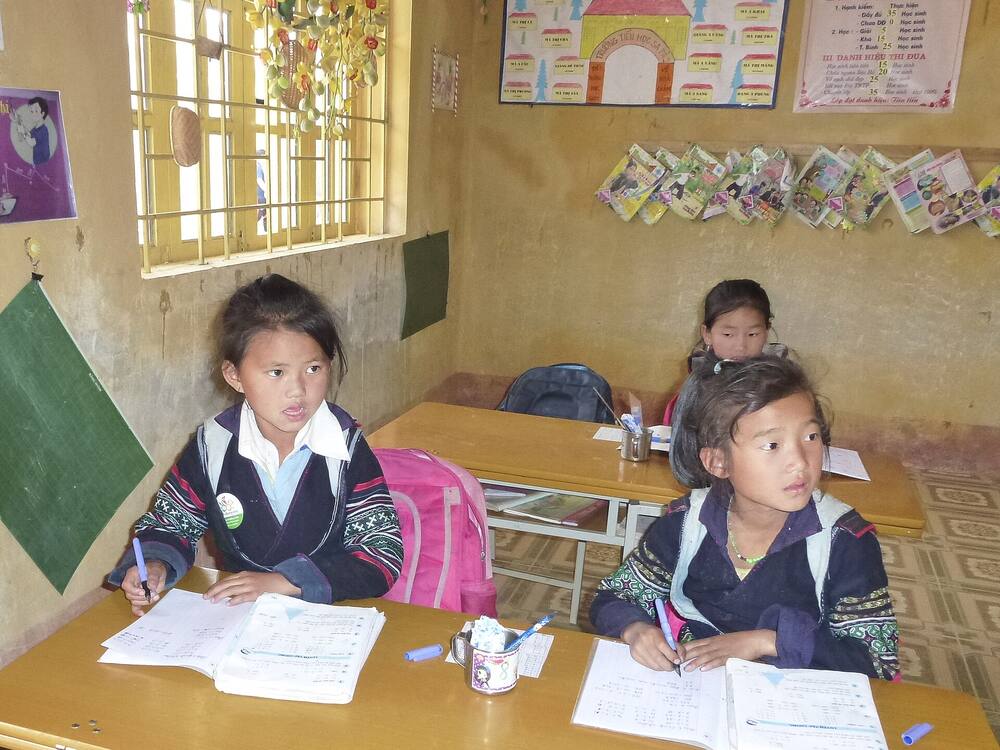 Hai em học sinh vùng cao ngồi học trong lớp