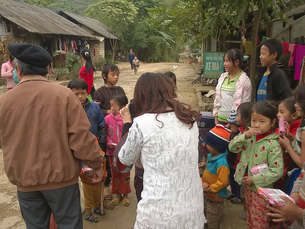 Người lớn trò chuyện với các em nhỏ và gia đình trong bản ở Hà Giang